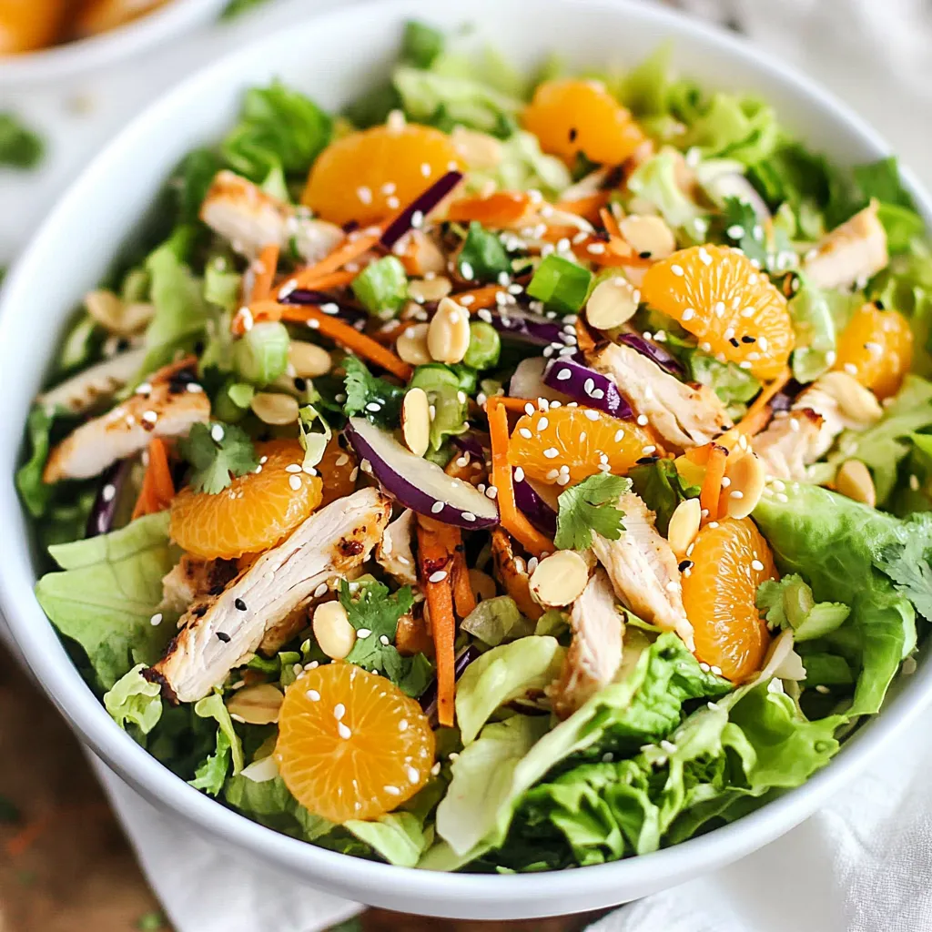 A bowl of salad with chicken, carrots, and oranges.