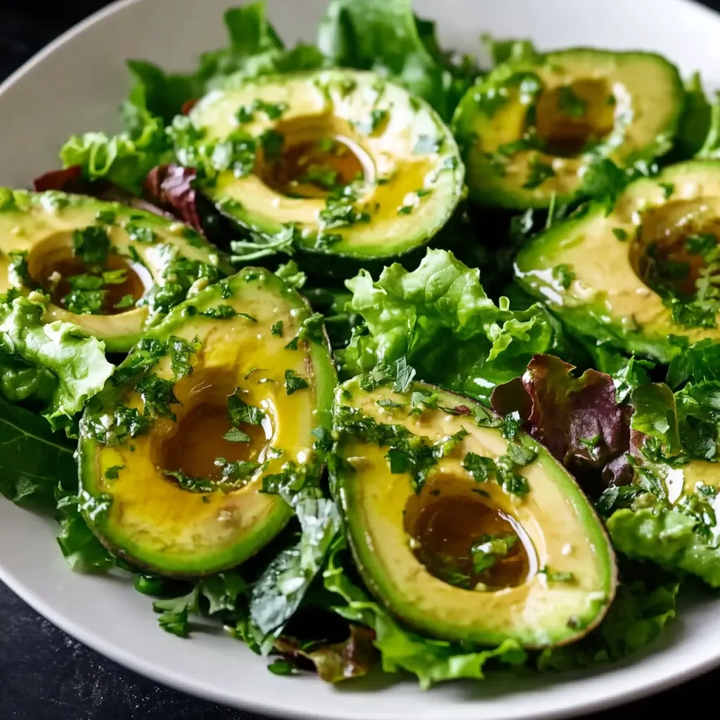 A white plate with a salad of lettuce and avocado.