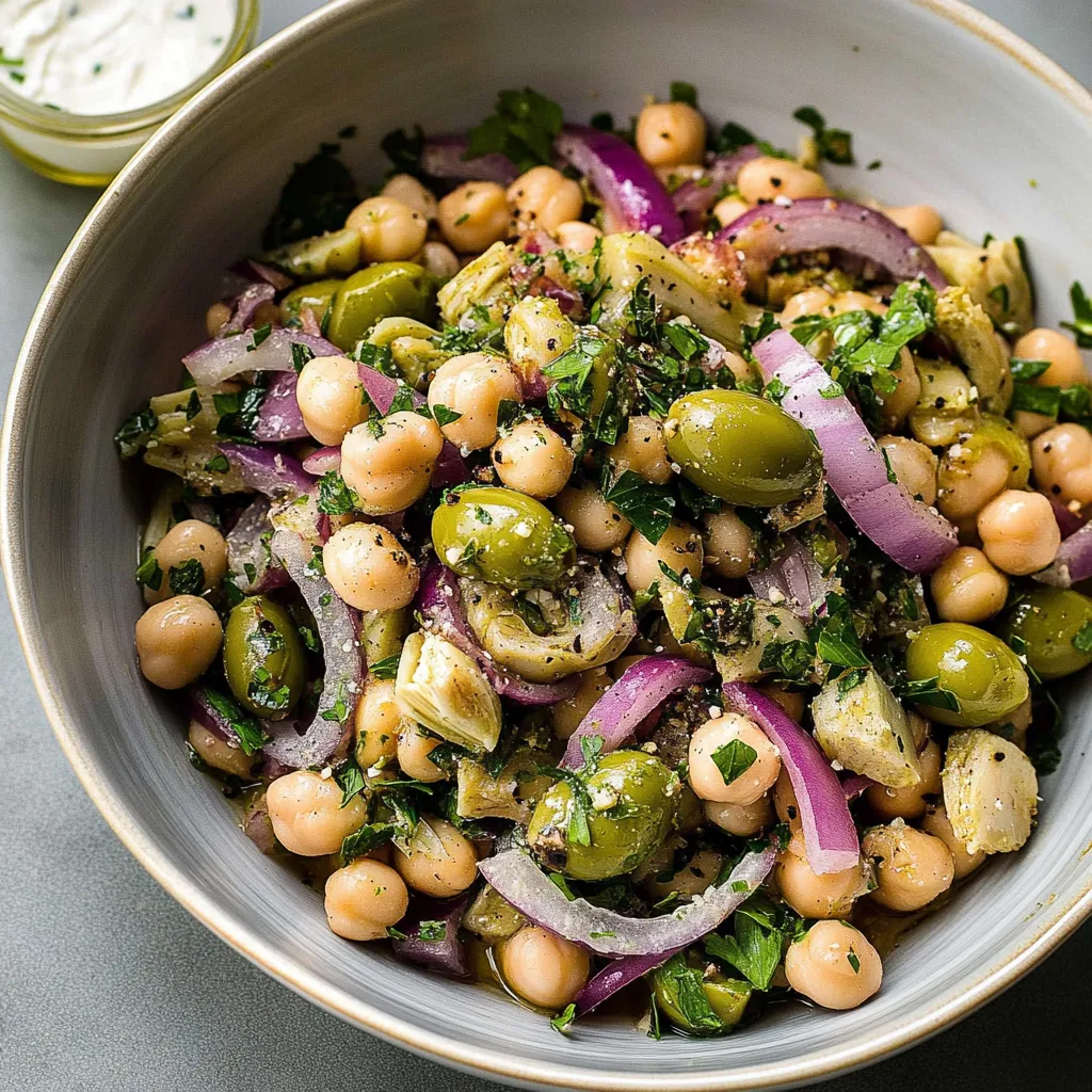 A bowl of food with chickpeas, onions, and olives.