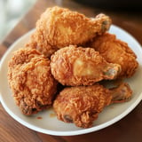 A plate of fried chicken is on a wooden table.