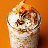 A glass of cereal with carrots and nuts.
