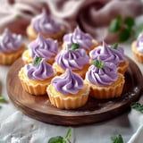 A plate of cupcakes with purple frosting.